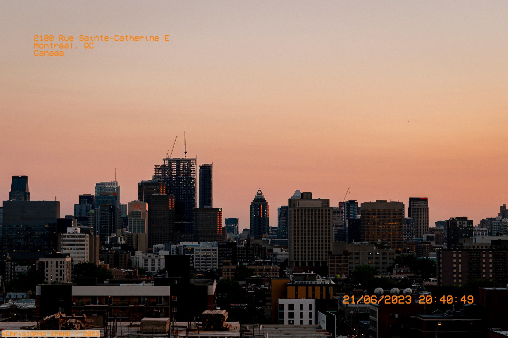 Panorama urbain de Montréal au crépuscule avec un ciel rose orangé.