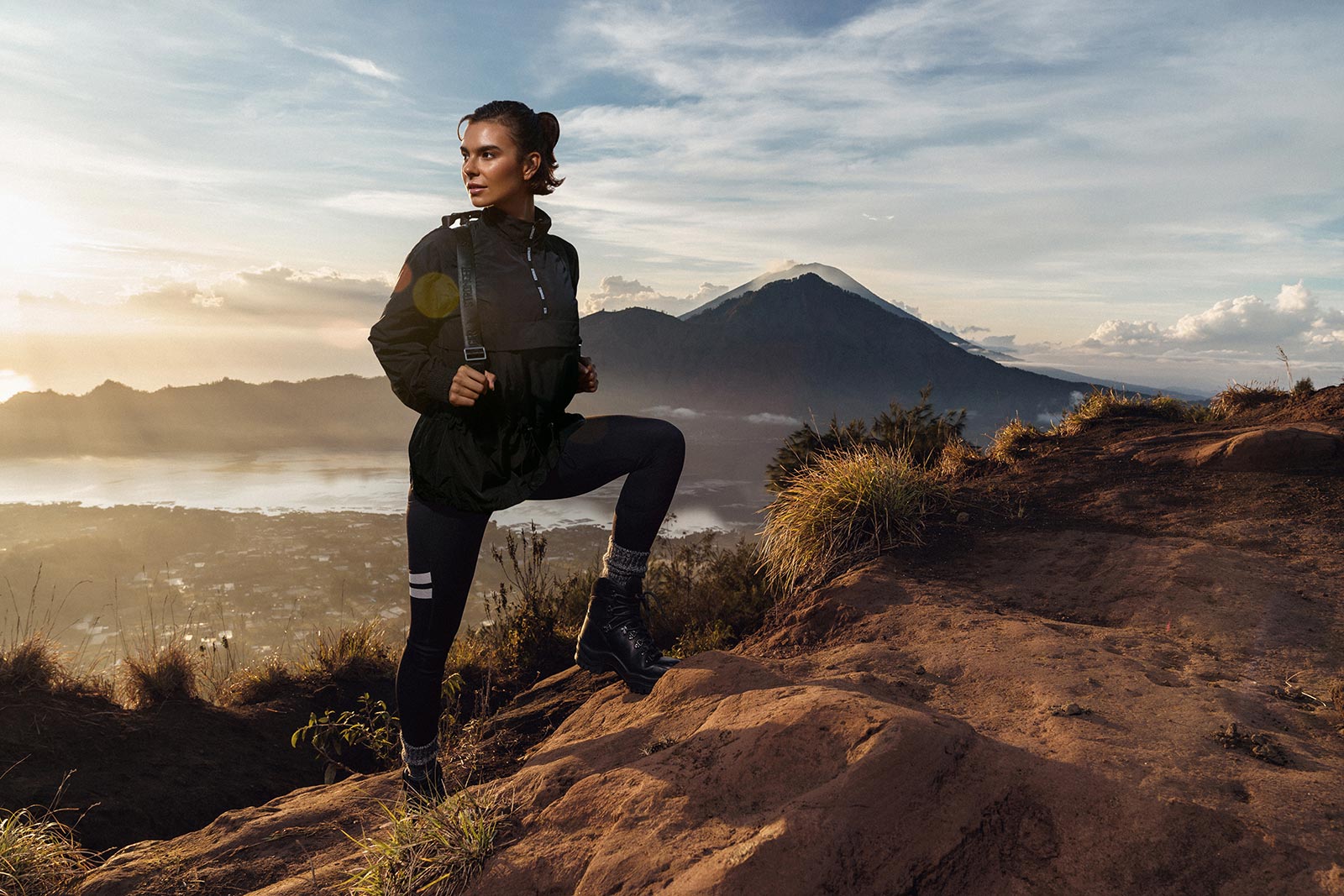 Female model in Stronger activewear on the volcanic terrain of Mount Batur, Bali, with Mount Agung in the background at sunrise — campaign photography produced by WeDo Creative