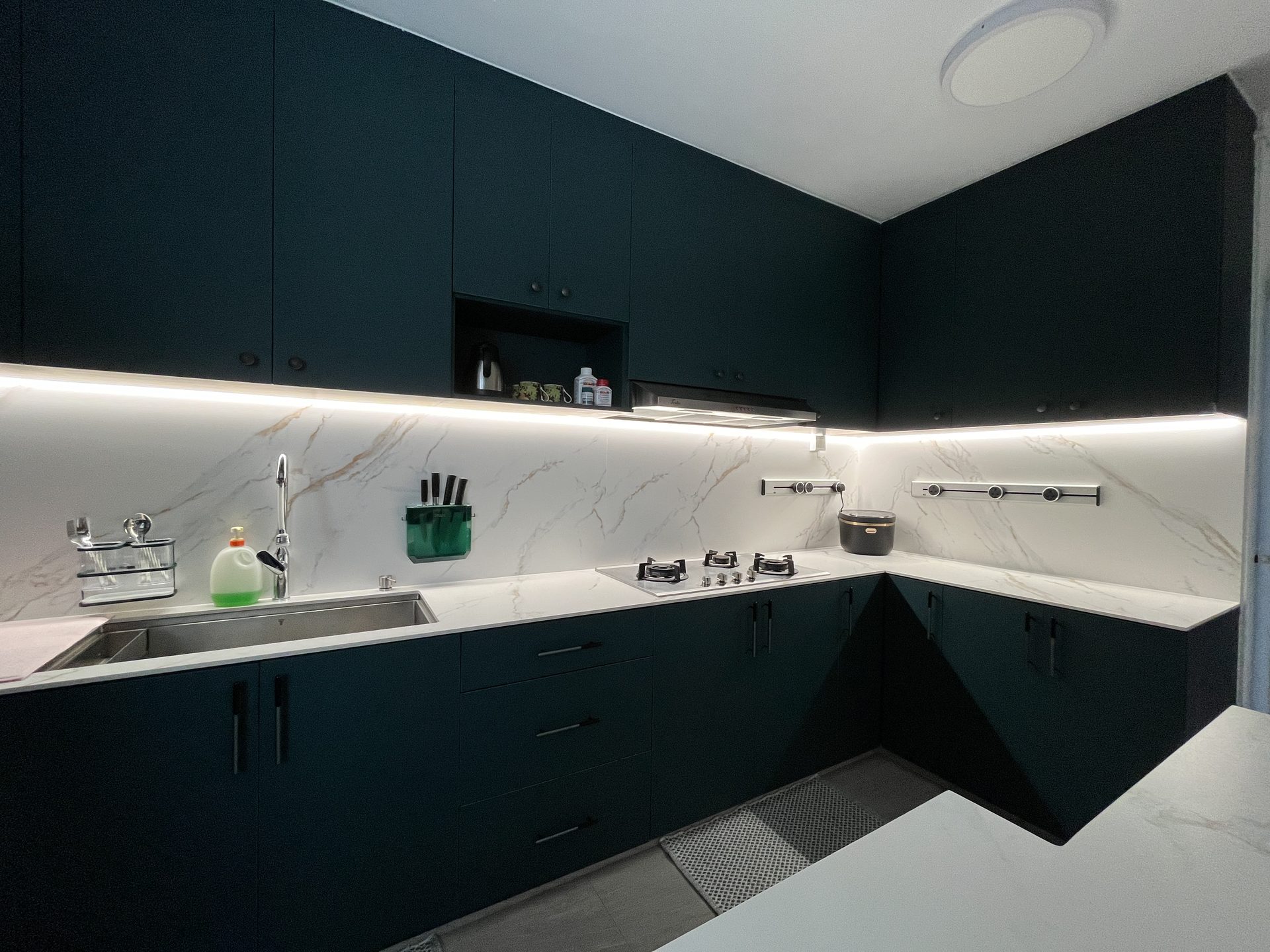 Mid grey floor tiles from Soon Bee Huat comtrast against teal coloured modern kitchen cabinets