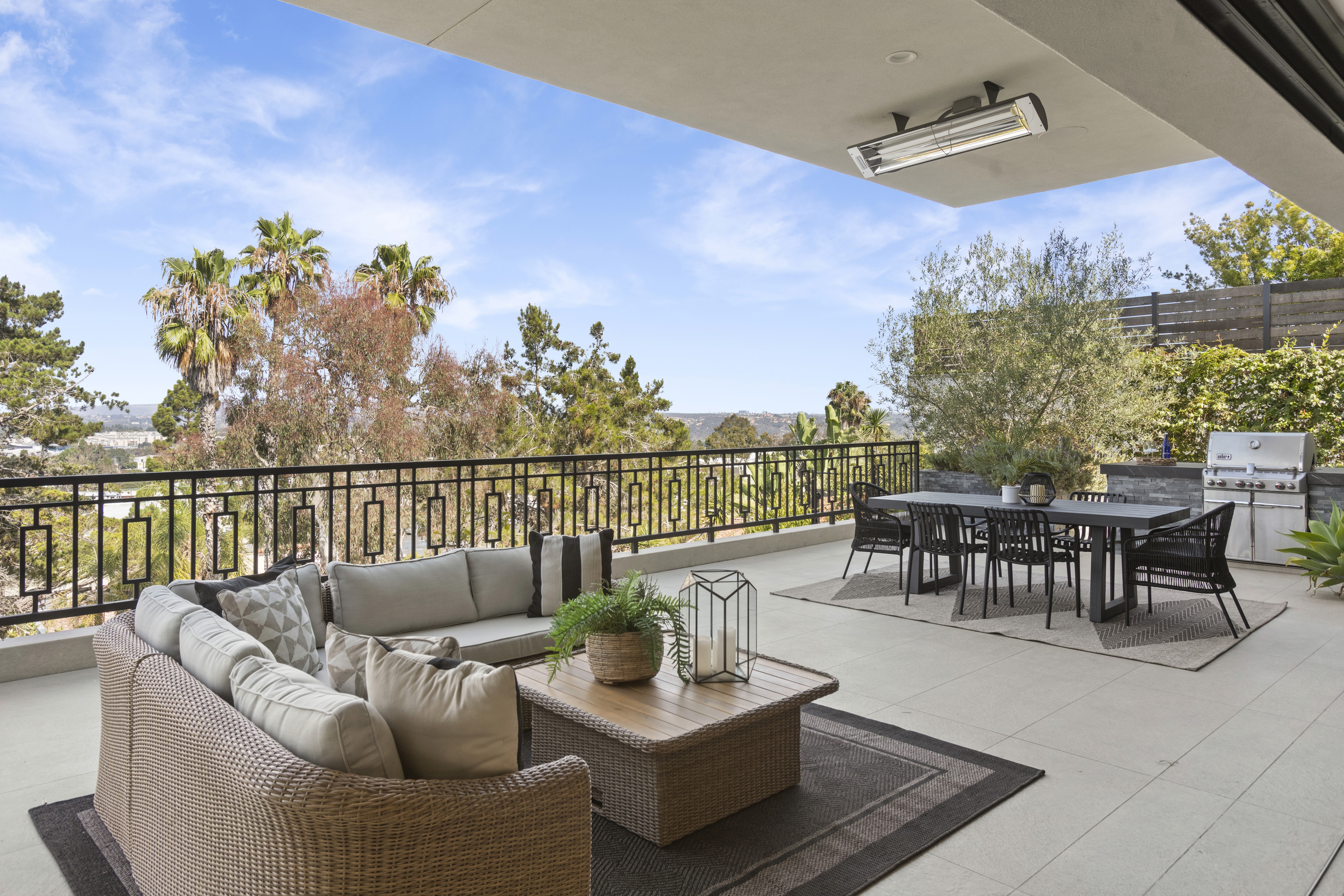 Staged covered balcony with a wicker sectional and dining set