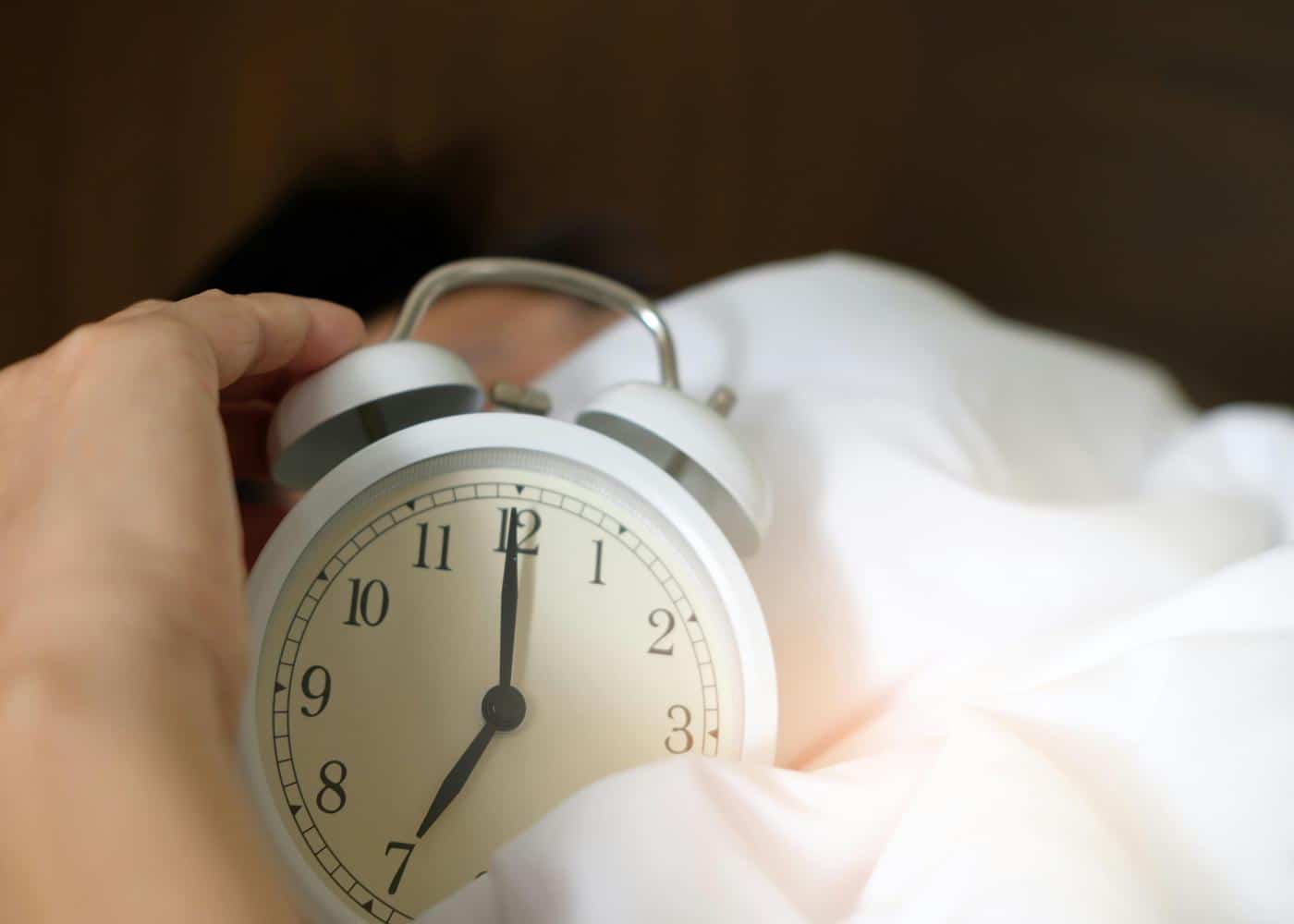 10-minute yoga nidra routine - Person hitting snooze on an alarm clock