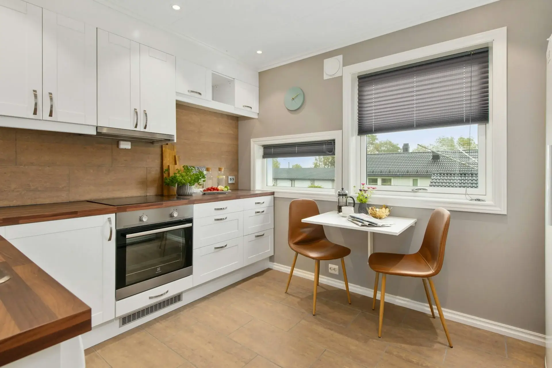 Compact white kitchen with wooden countertops and small dining table.