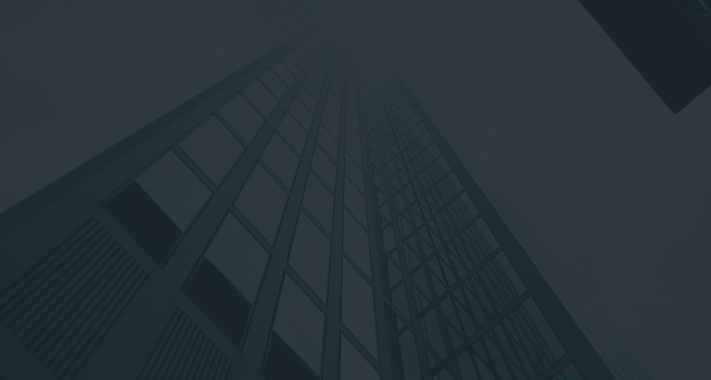 Low-angle view of a modern skyscraper fading into the fog, with a dark, moody atmosphere.