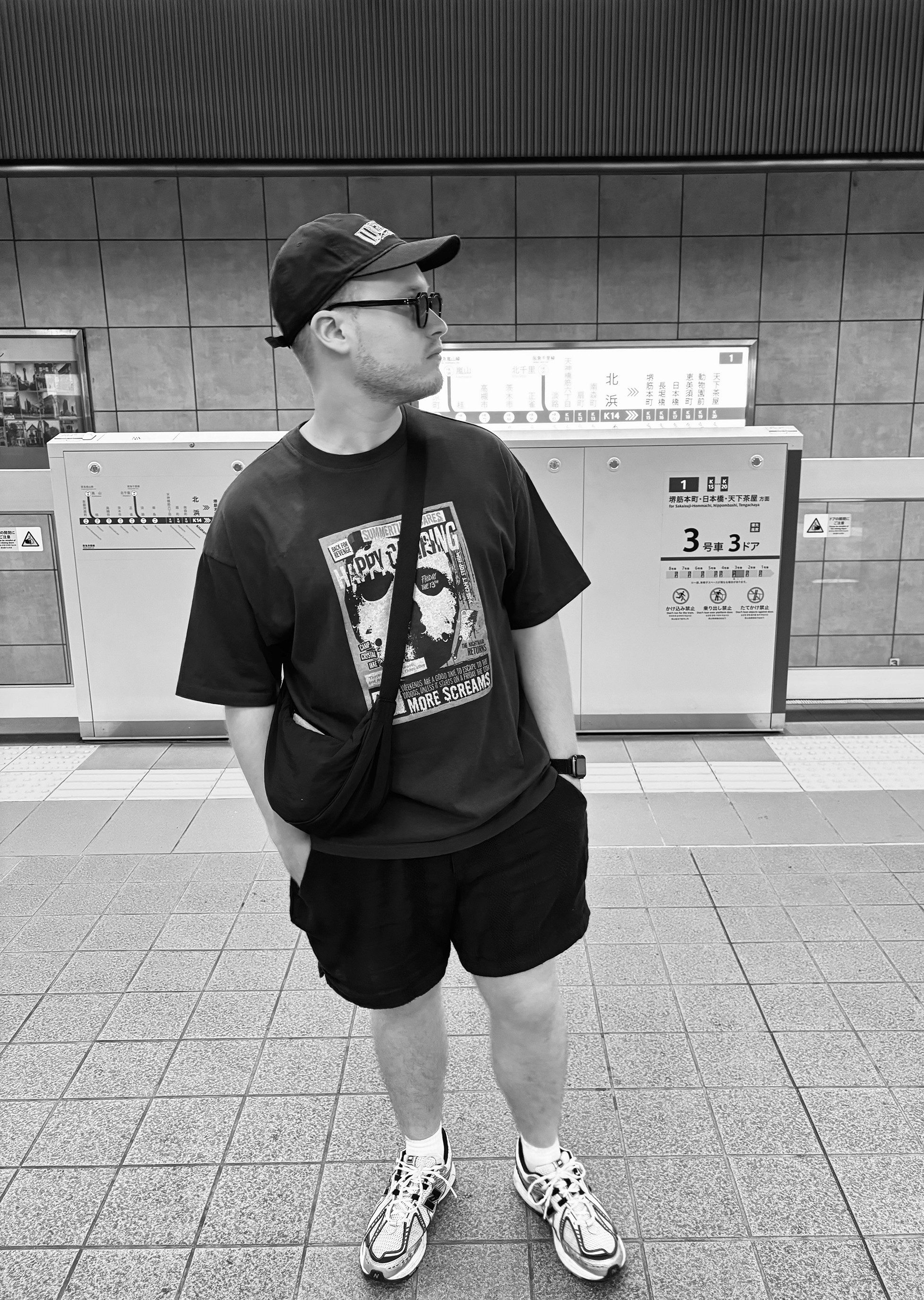 Wizzle, a German music producer, stands in a subway station wearing a cap, sunglasses, and a graphic t-shirt. He looks to the side with a thoughtful expression, captured in black and white.