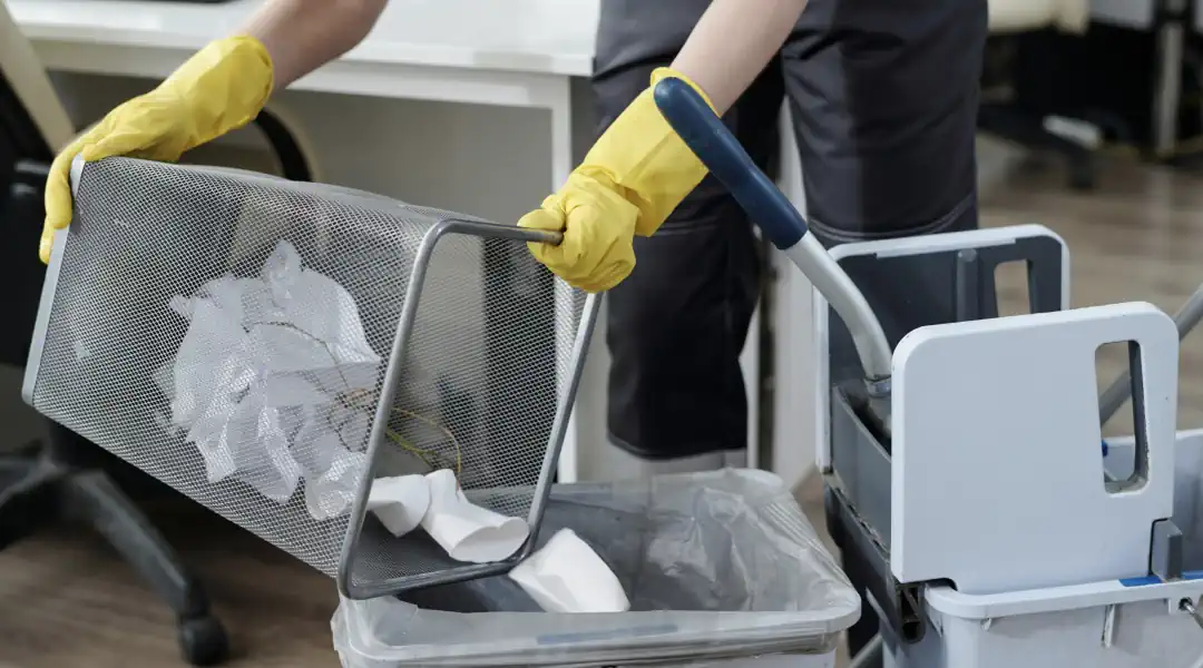 Raikaslinja person wearing yellow gloves holding a trash can