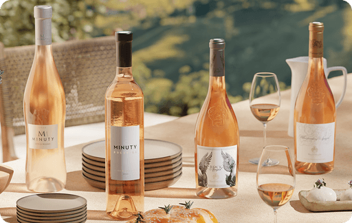 Lifestyle shot of rosé wine bottles on set table against Mediterranean background with mountains