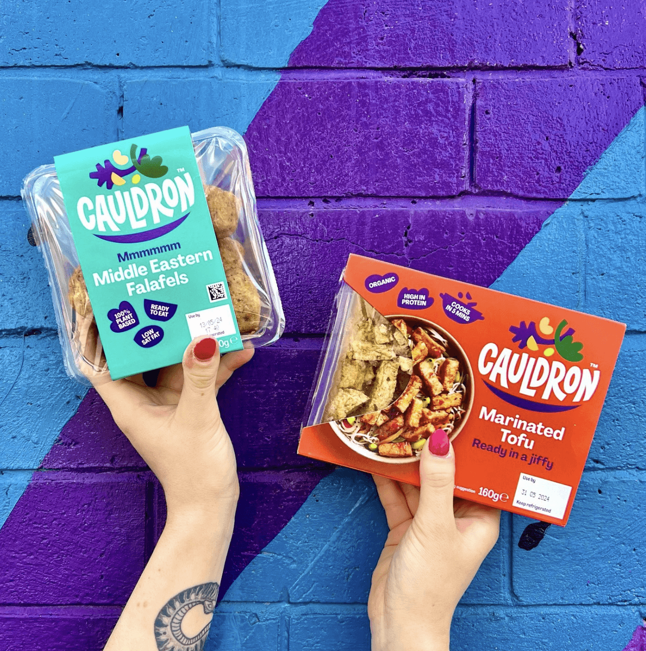 Holding Cauldron products near street art