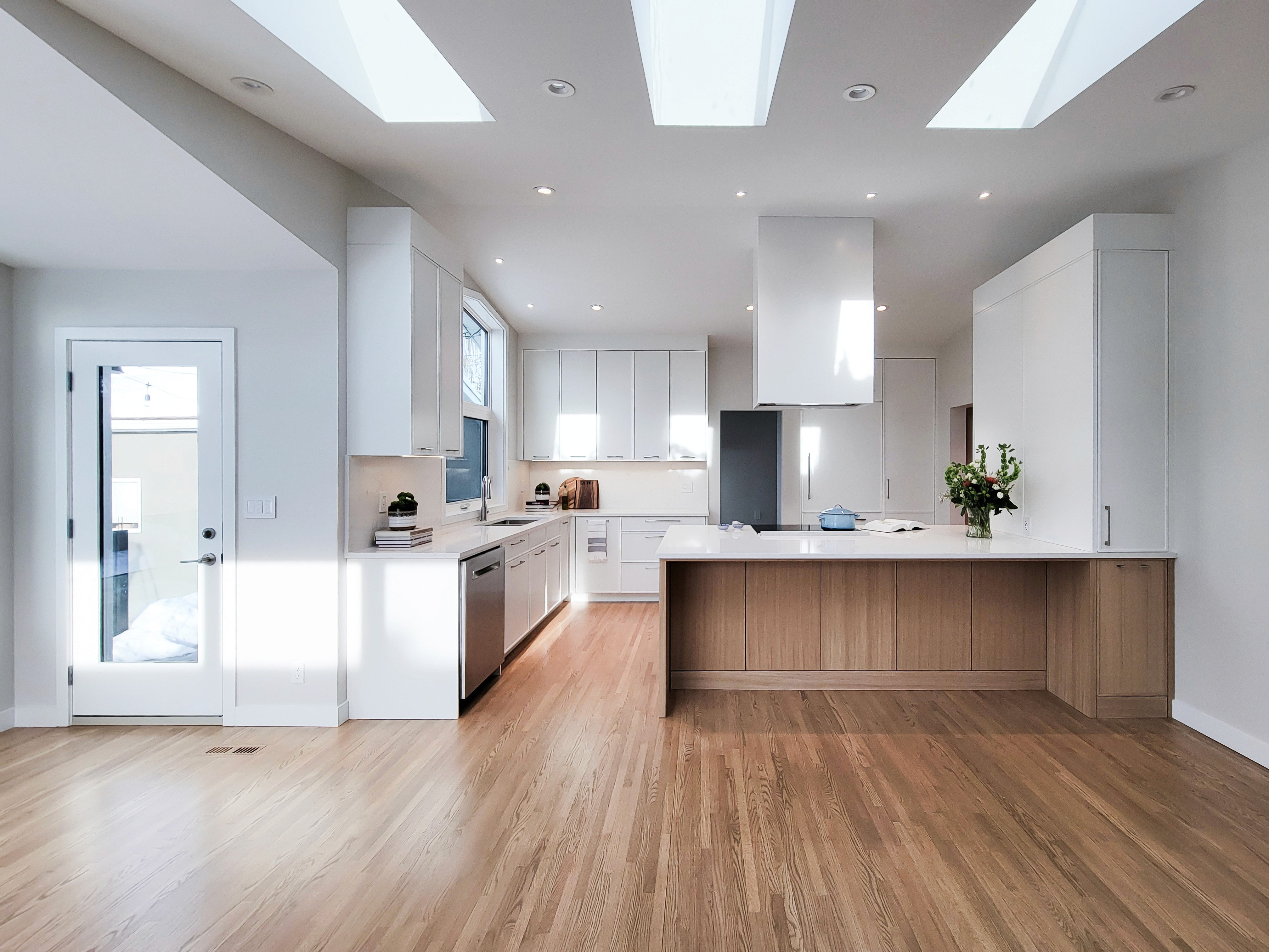 Image of Modern kitchen interior with island, skylights, and hardwood floors, showcasing KHD Homes design-build expertise.
