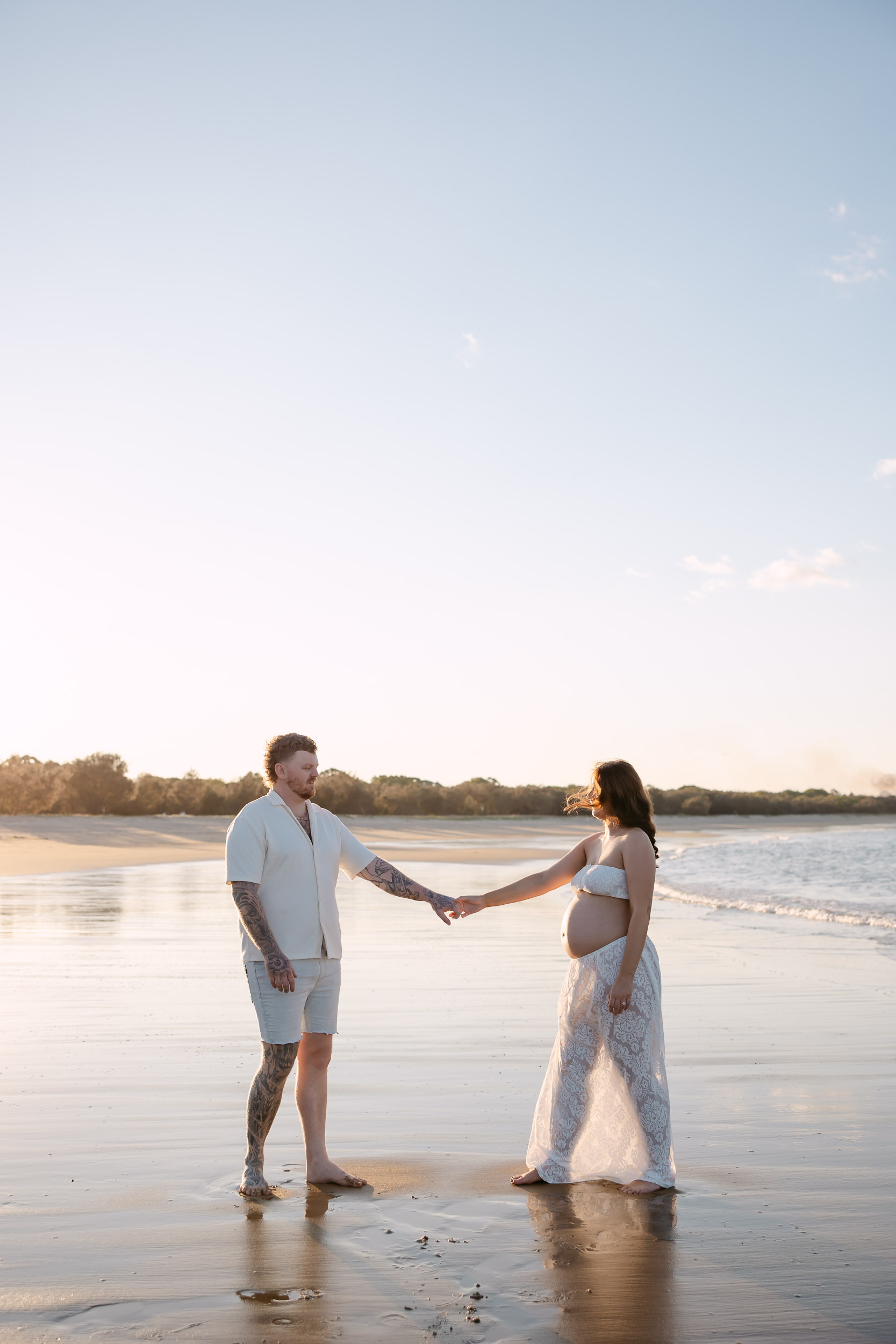 couple holding hands on the beach during maternity photoshoot in Mackay