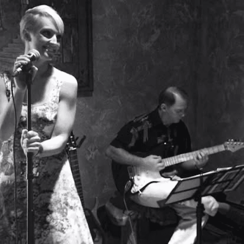 Jeannette Papadakis performing with a guitarist during a live music performance.
