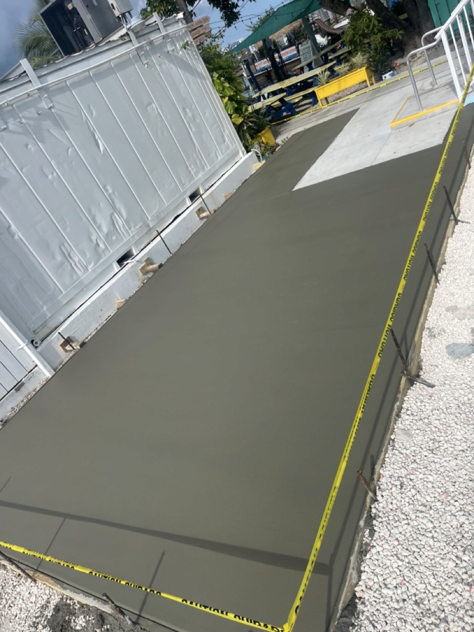 A serene outdoor lounge area with two chairs surrounded by lush greenery and natural light streaming in.