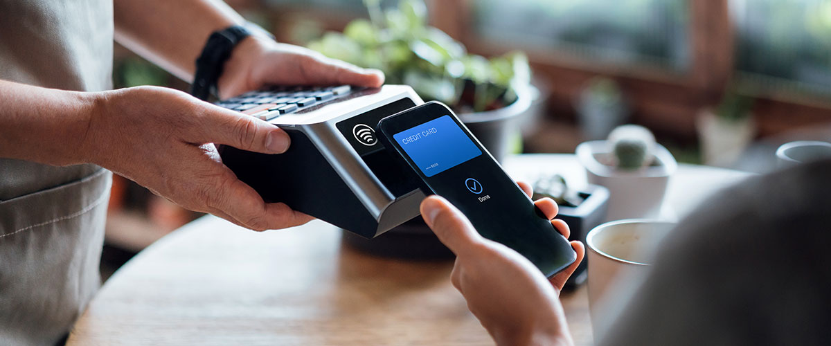 A close-up of hands using a payment terminal to complete a transaction at a retail or food venue.