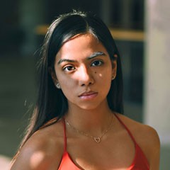 Fotografía de una mujer joven de piel morena y cabello largo negro, con expresión reflexiva; representa el perfil de una madre de familia interesada en servicios de salud mental y bienestar emocional para fortalecer sus vínculos personales.