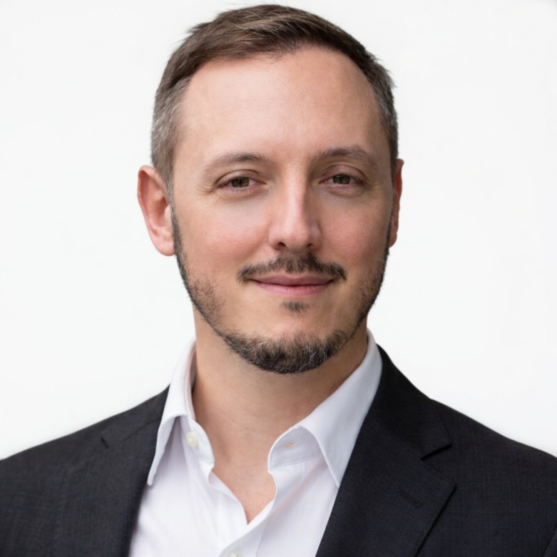 Portrait of a man in a suit, smiling. Professional headshot.