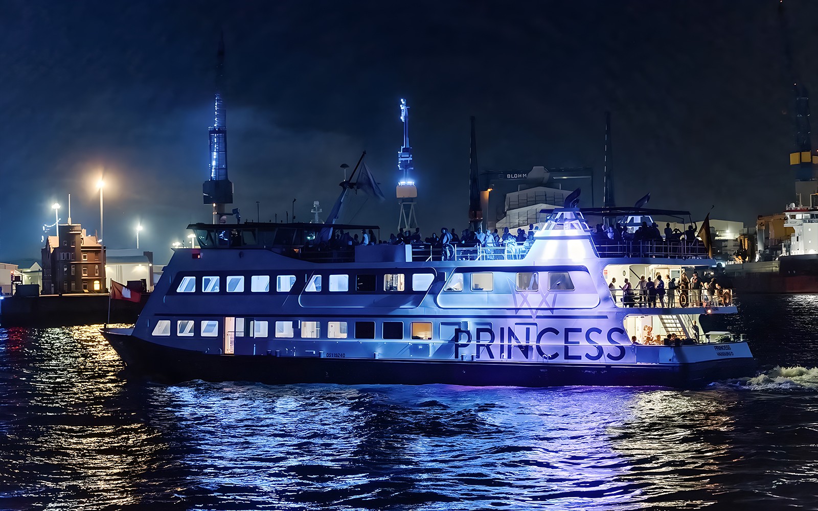 Large ship illuminated at night during 1.5h Grand Evening Lights Cruise.