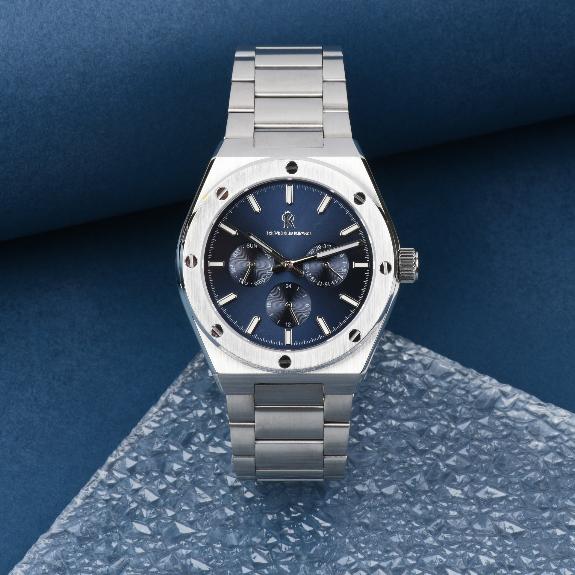 product photography of silver wristwatch on blue stone surface