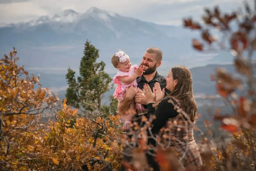 A family enjoys one of their Aspen Family Photo Shoots on a mountain overlook with snow-capped peaks in the background.