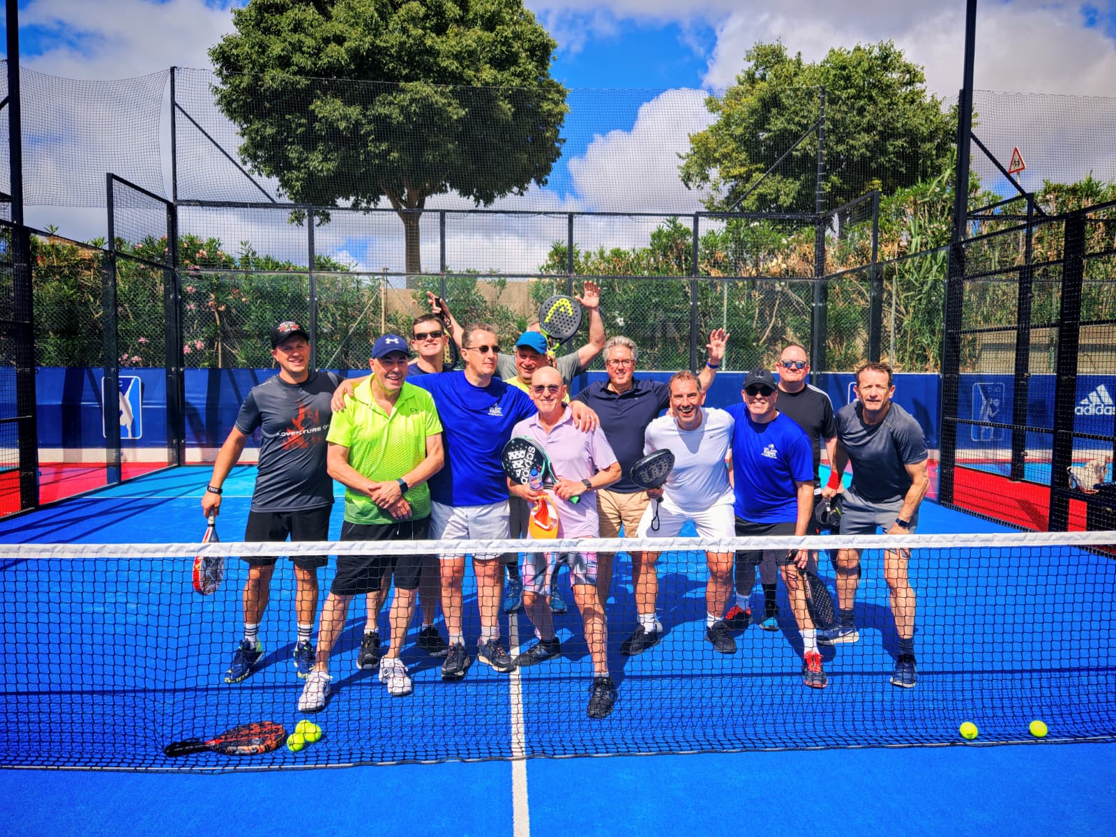 Cozy reading nook with sofa, chair, and plants inside a glass cabin with mountain forest views.