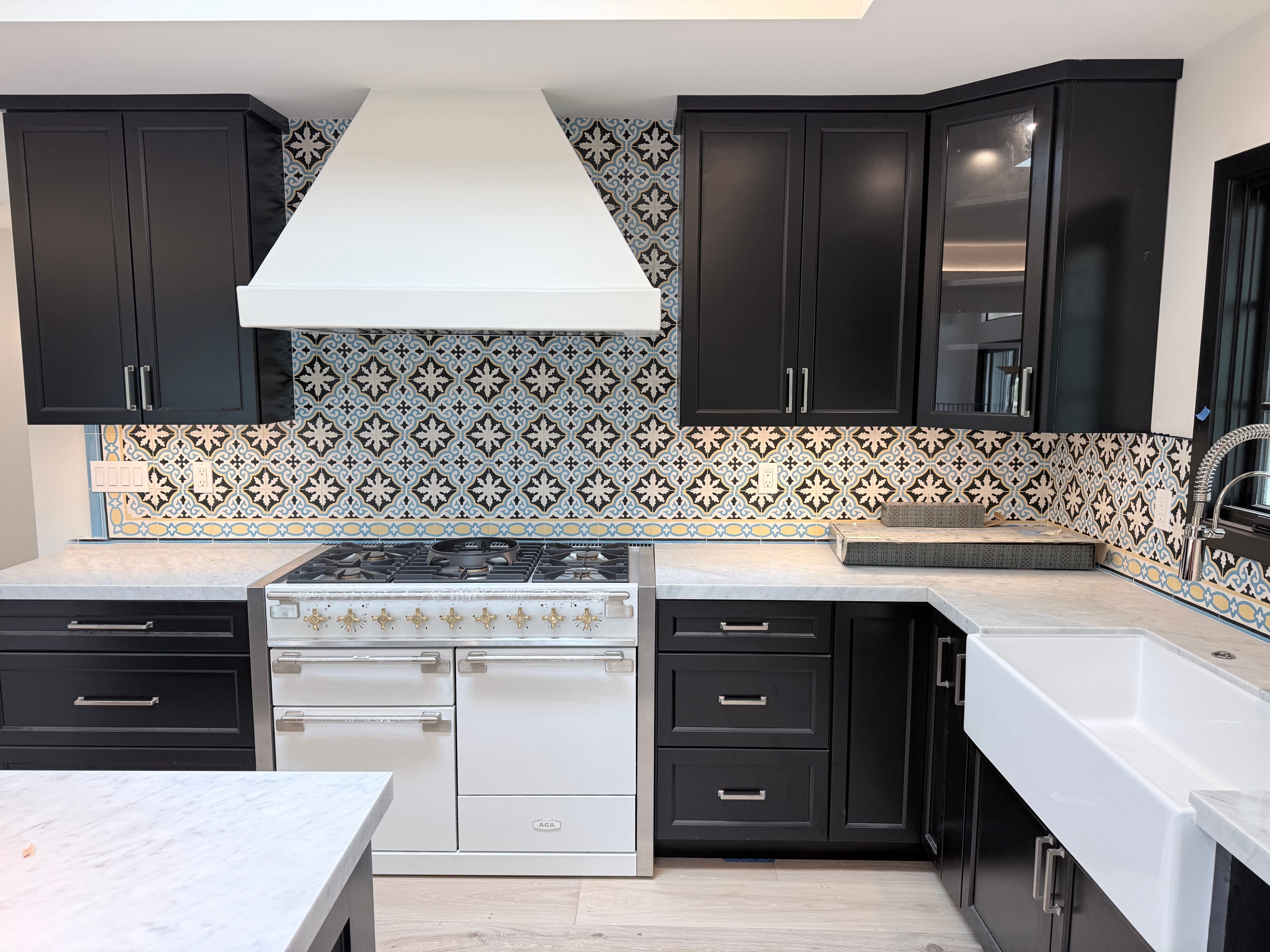 Finished kitchen at 1158 Chaparral, black shaker cabinetry, patterned tile backsplash, marble counters, professional range.