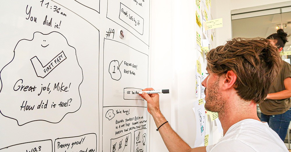 A facilitator annotating a sketch on a whiteboard  