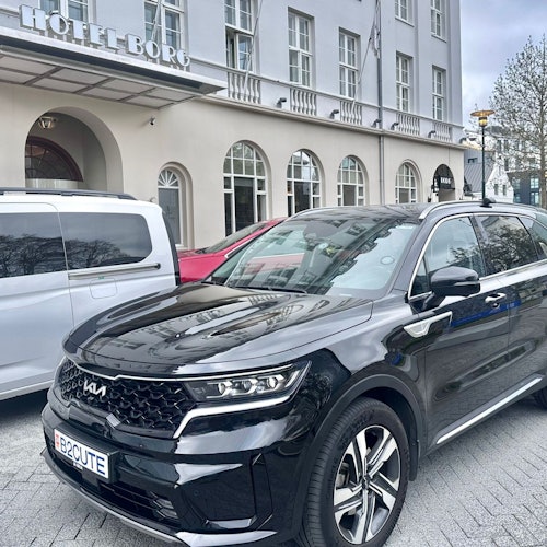 Un SUV negro con una matrícula personalizada que dice B2CUTE está estacionado frente a un hotel con ventanas arqueadas y un letrero del Hotel Borg.