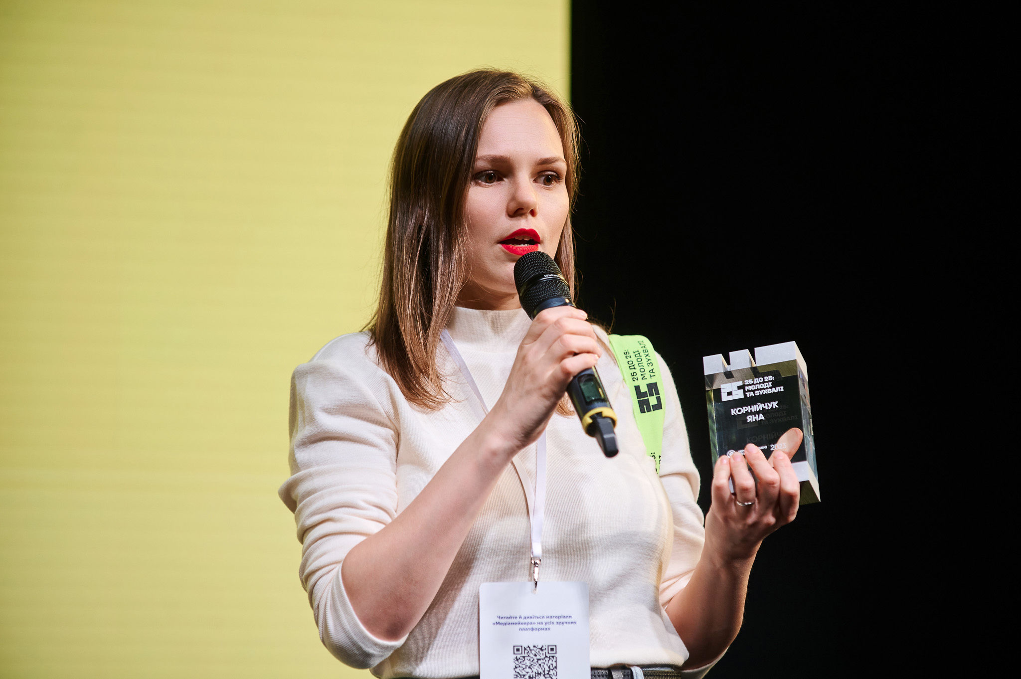 A speaker presenting at an AI conference in front of an audience, discussing real-world approaches to building AI products.