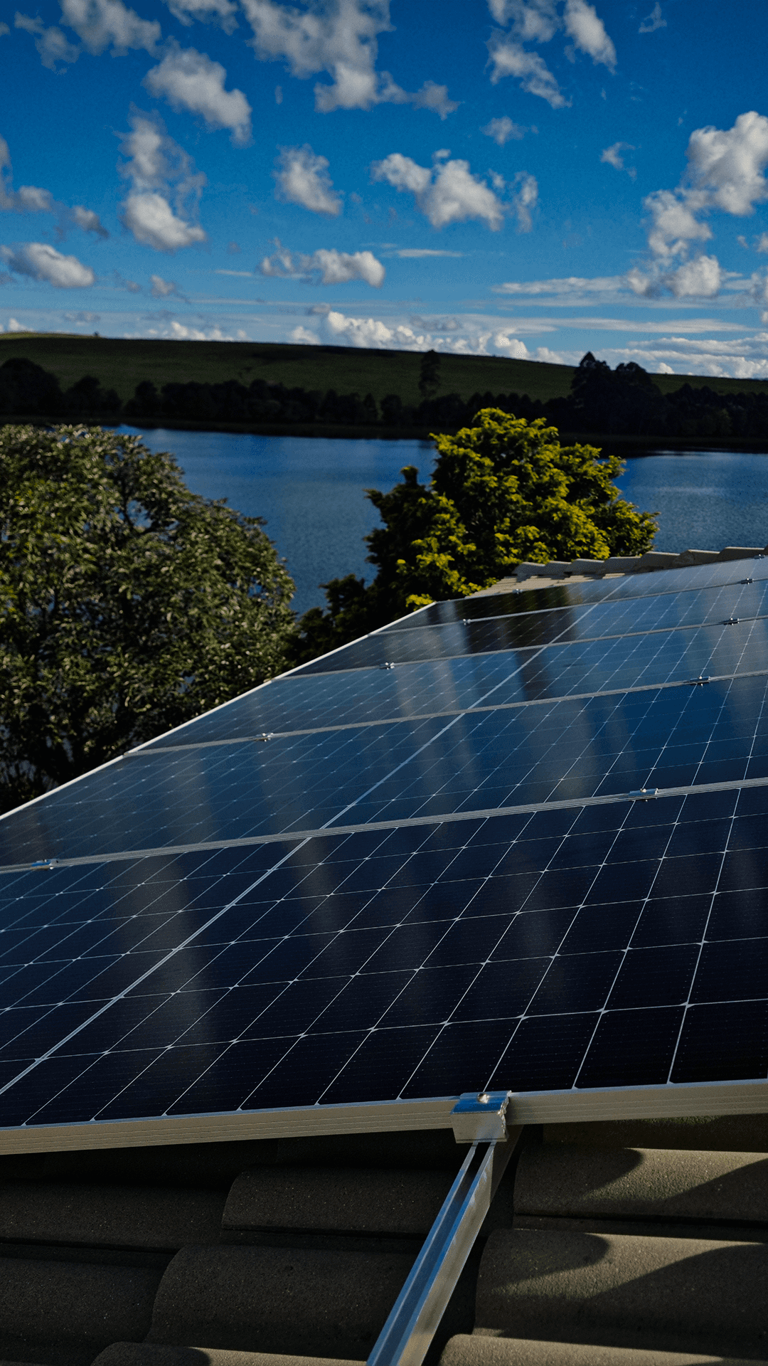 A smiling woman with her arms crossed, standing against a dark green background. She has long, dark hair.
