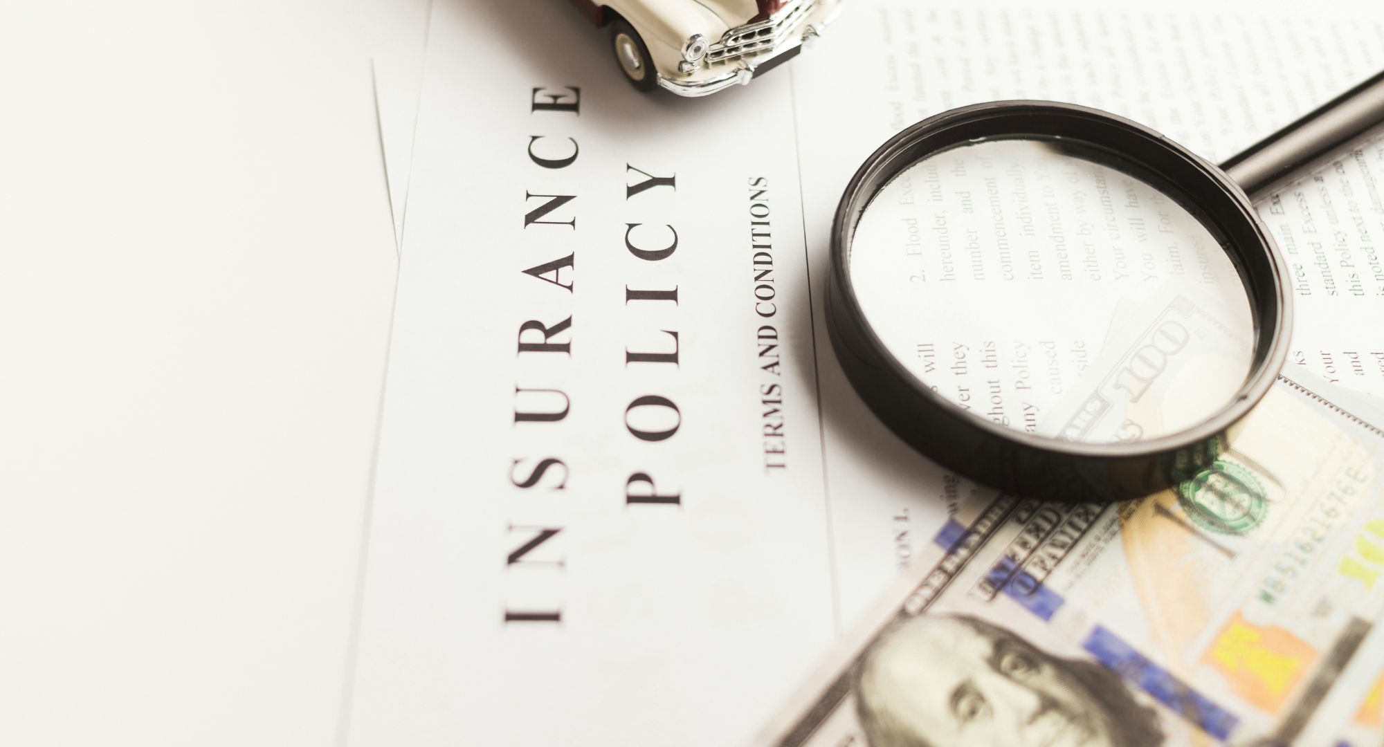 uma lupa sob um contrate de seguro e um nota de dólar