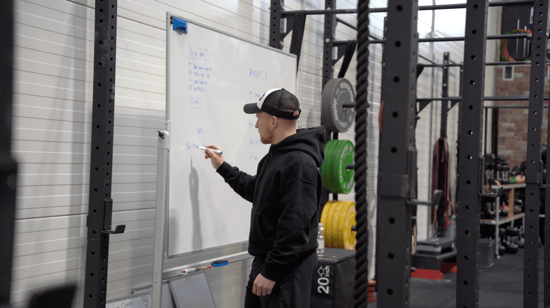 Coach Séb écrivant au tableau blanc pour le cours de CrossFit