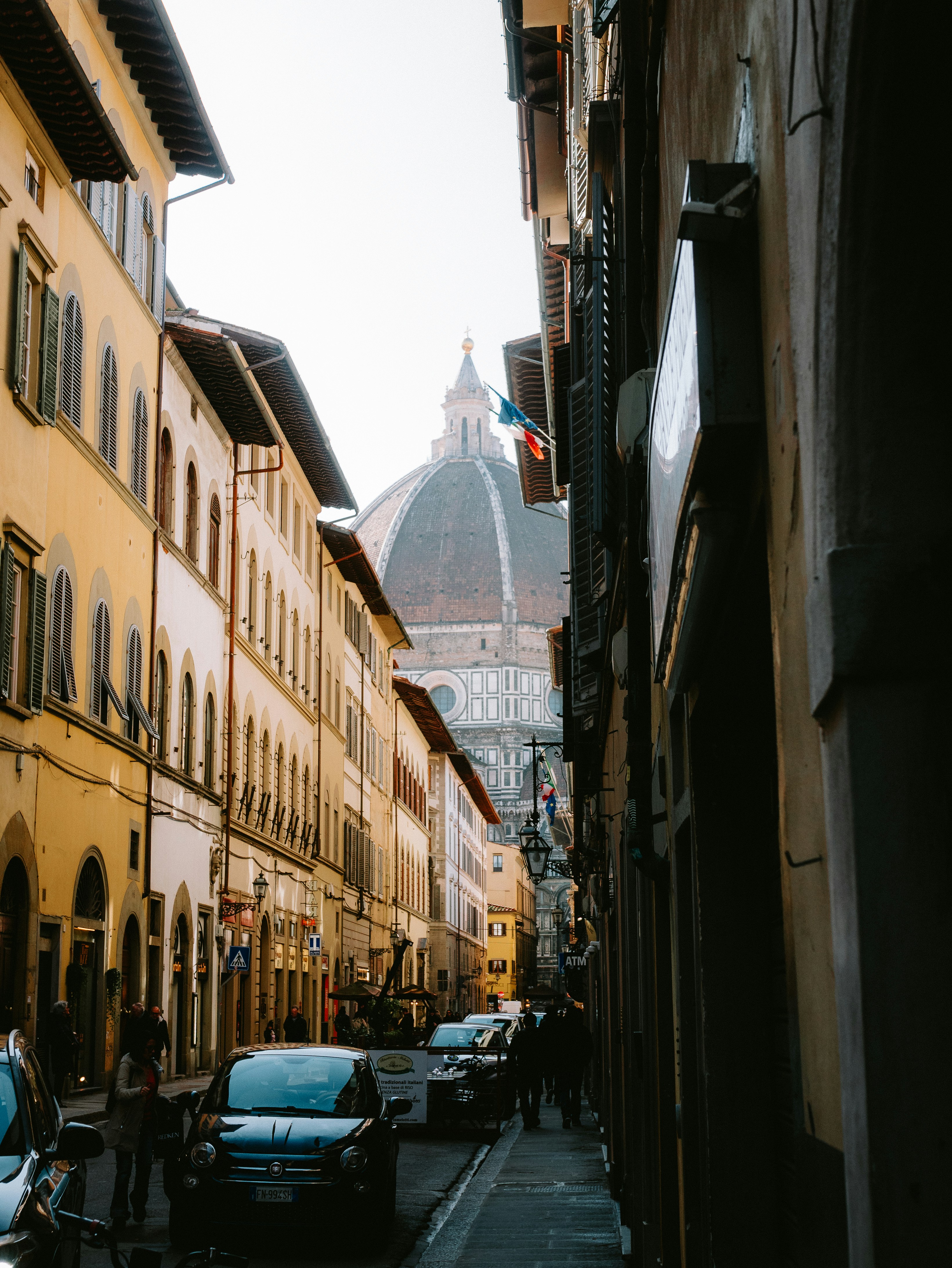 A narrow city street lined with parked cars