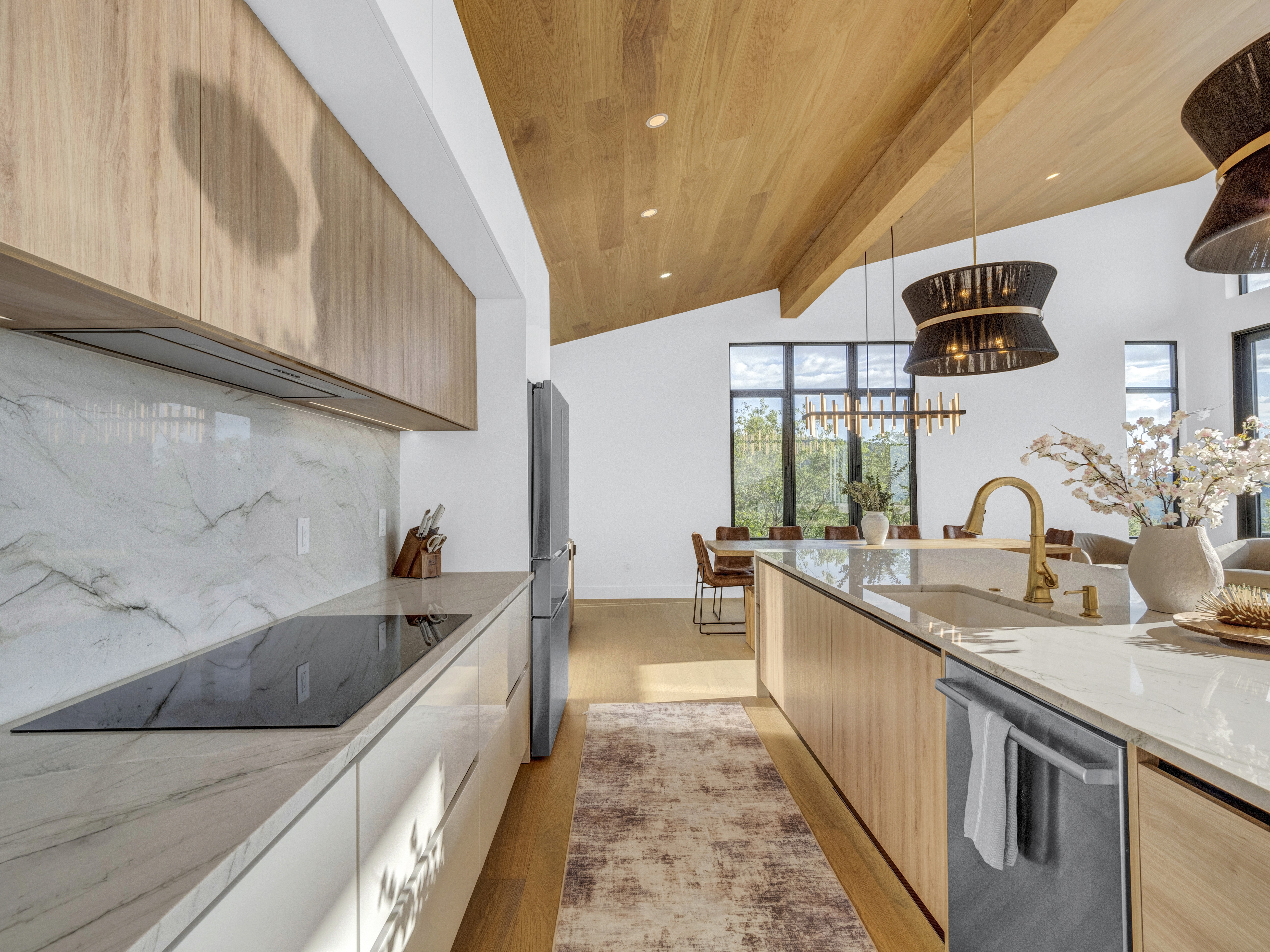 A clean, minimalist kitchen view showing the induction cooktop, marble backsplash, and seamless cabinetry