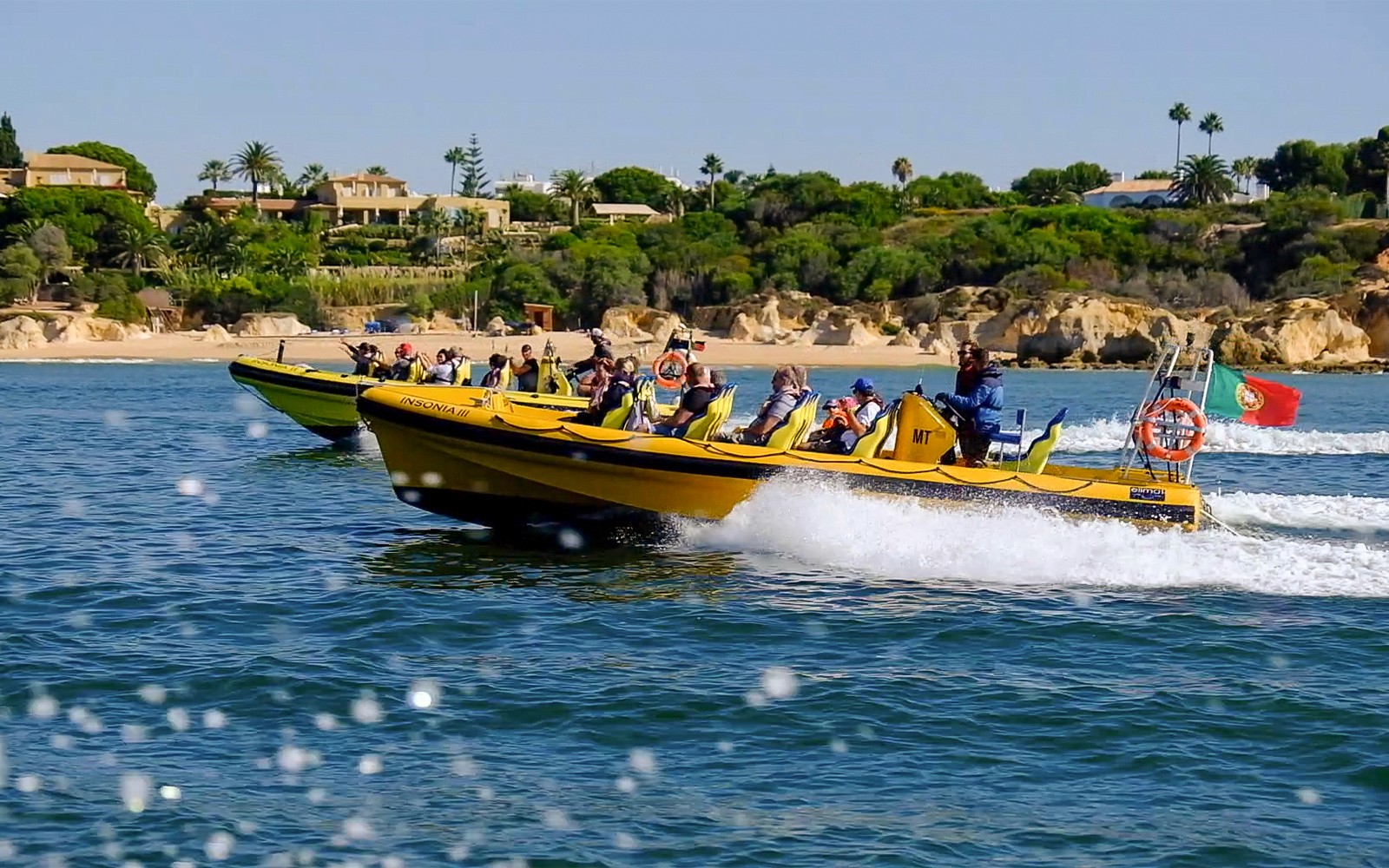 Speedboats with tourists on a dolphin watching and cave cruise near Algarve coast, Portugal.