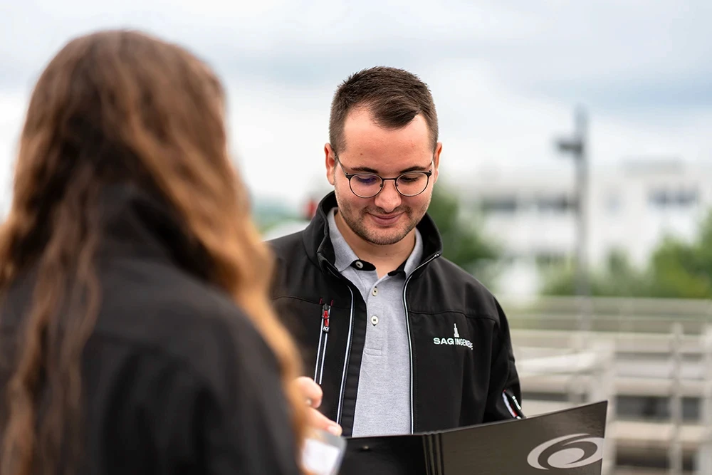 Werkstudent Elektroingenieur von SAG Ingenieure bei der technischen Begehung einer Kläranlagen- bzw. Infrastrukturbaustelle. Der Student prüft Unterlagen vor Ort und unterstützt das Projektteam bei Aufgaben der Elektro-, Mess-, Steuer- und Regelungstechnik.
