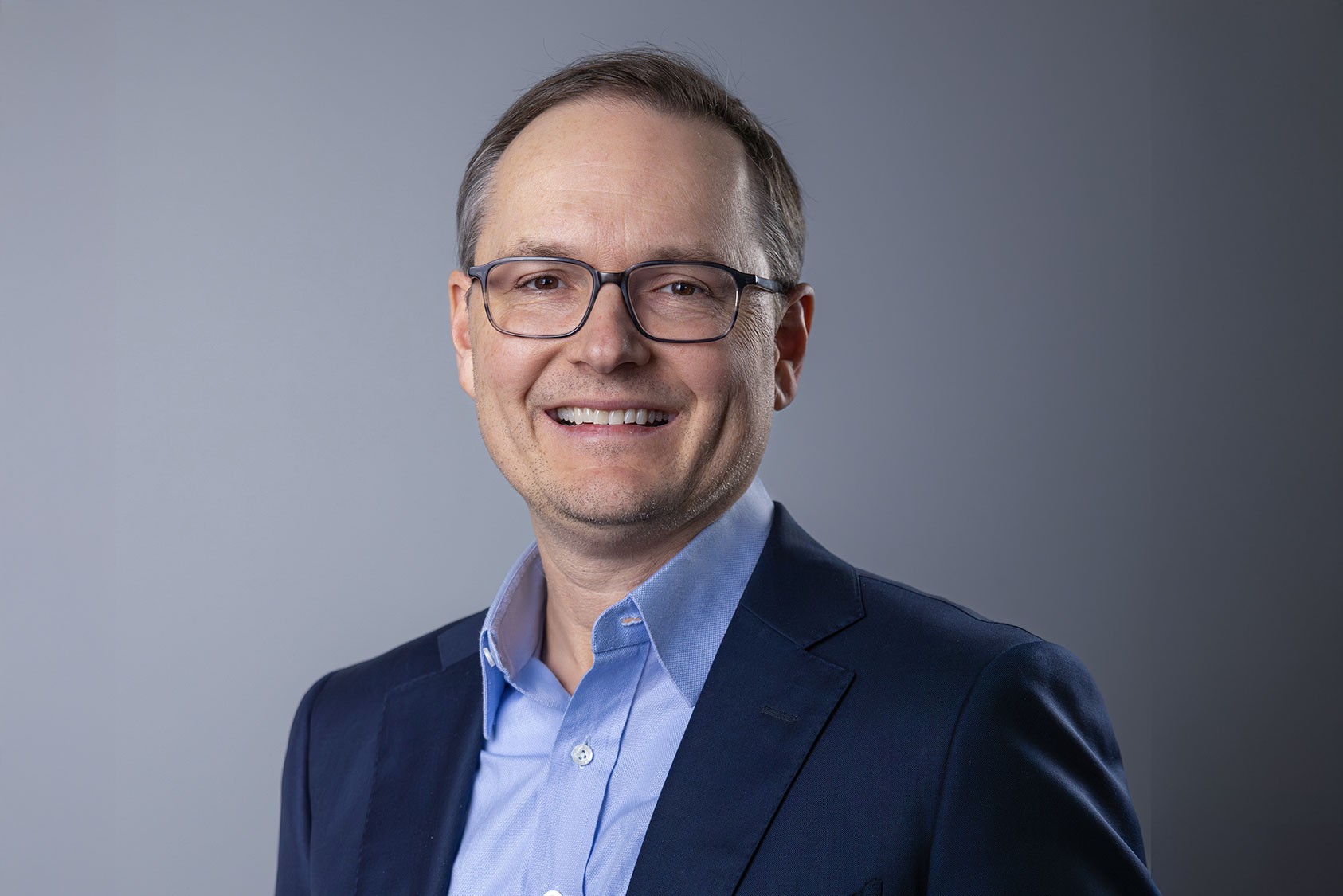 Scott Niewland, SteriMax Chief Financial Officer: Smiling in professional business attire against a neutral studio background.
