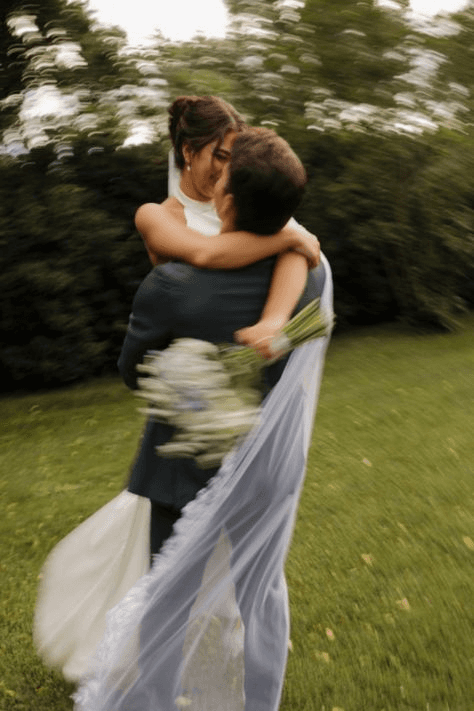 Dreamy candid wedding shot of a bride and groom in a tender embrace, with natural outdoor surroundings, capturing the love and authenticity typical of candid photography.