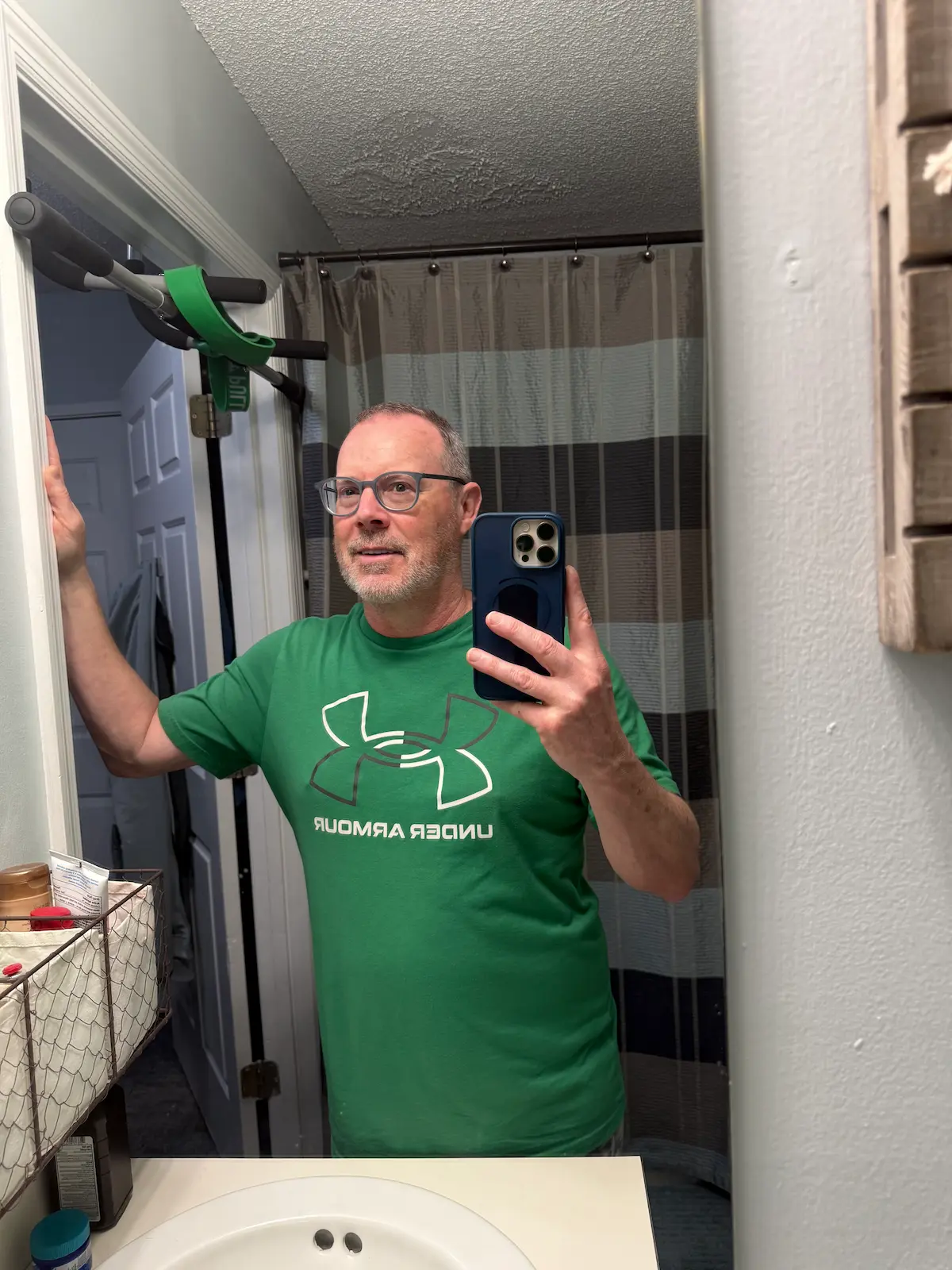 Man taking a selfie in a bathroom mirror while looking at his reflection.