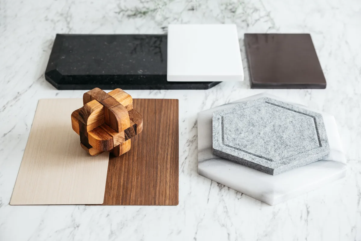 Sélection de matériaux pour une rénovation intérieure, échantillons de granit noir, carrelage blanc, faïence, noyer et marbre disposés sur plan de travail en marbre