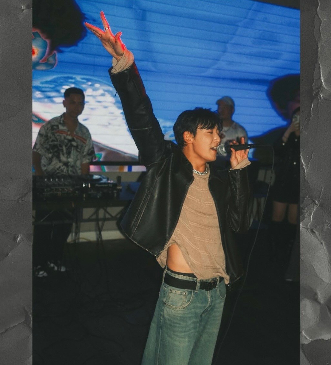 alt="kevin woo raising his arm and singing to his fans"