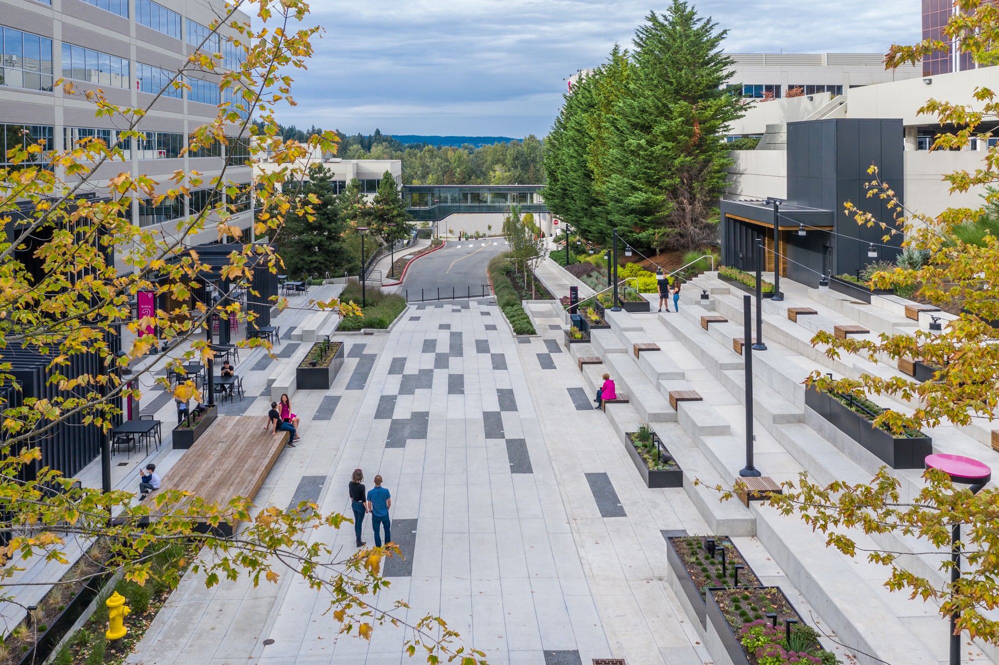 A midday aerial view of the plaza center, showcasing the rhythmic interplay of dark gray pavers against the light gray hardscape.