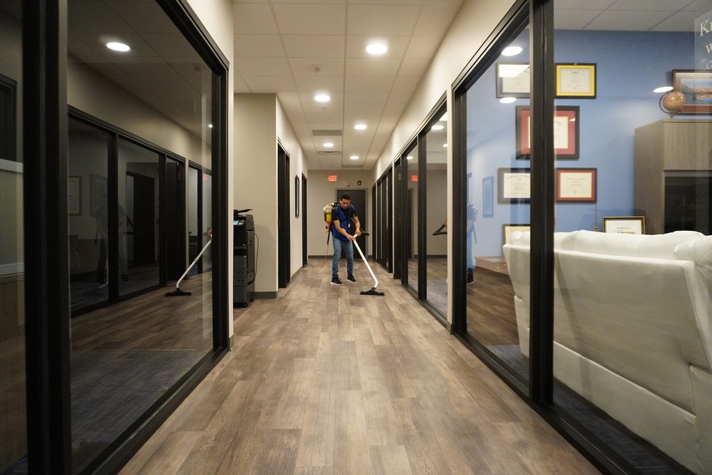 Ziva cleaning service vacuuming the office hallway