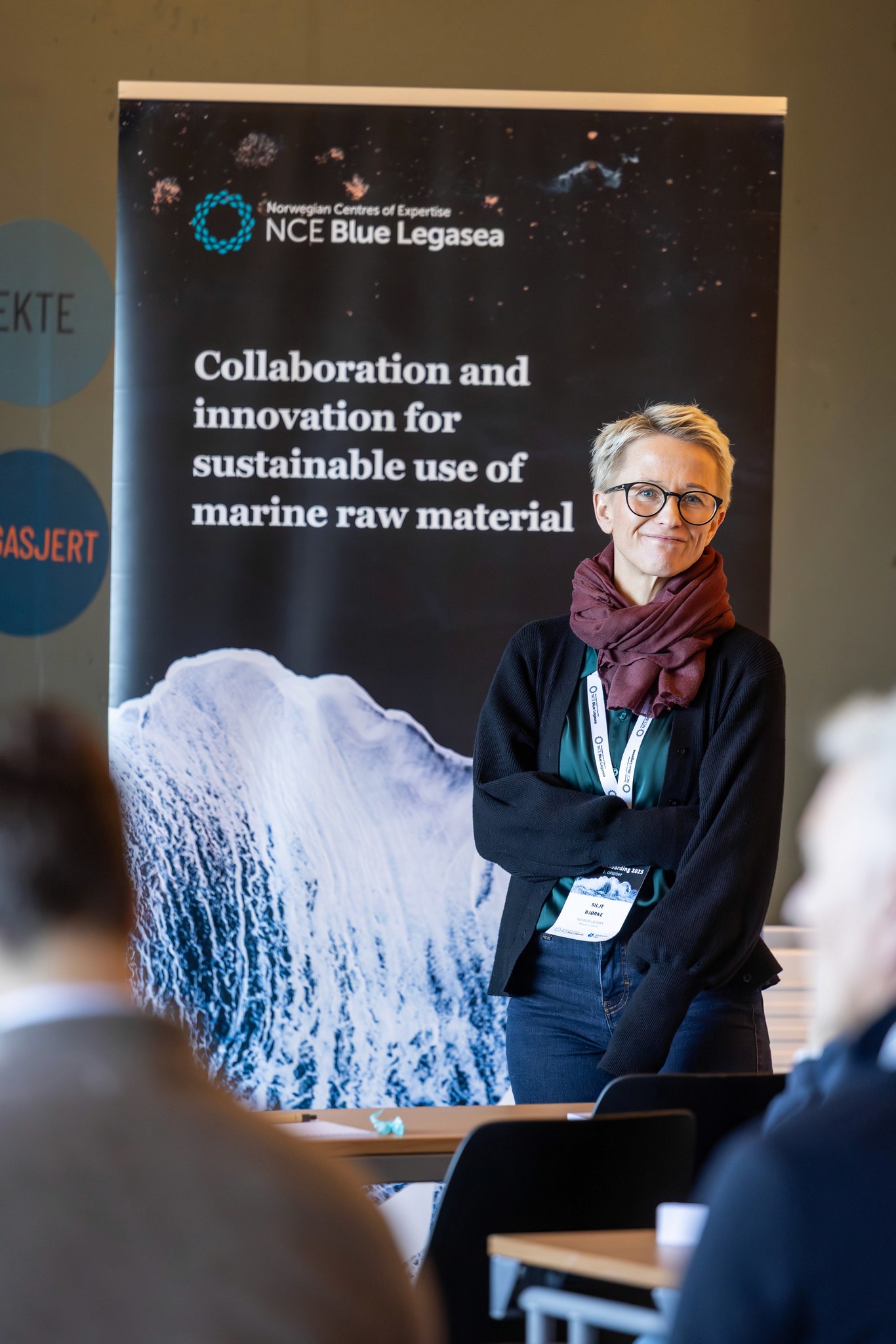 A person stands next to a banner, engaging with others in a setting focused on community and innovation.