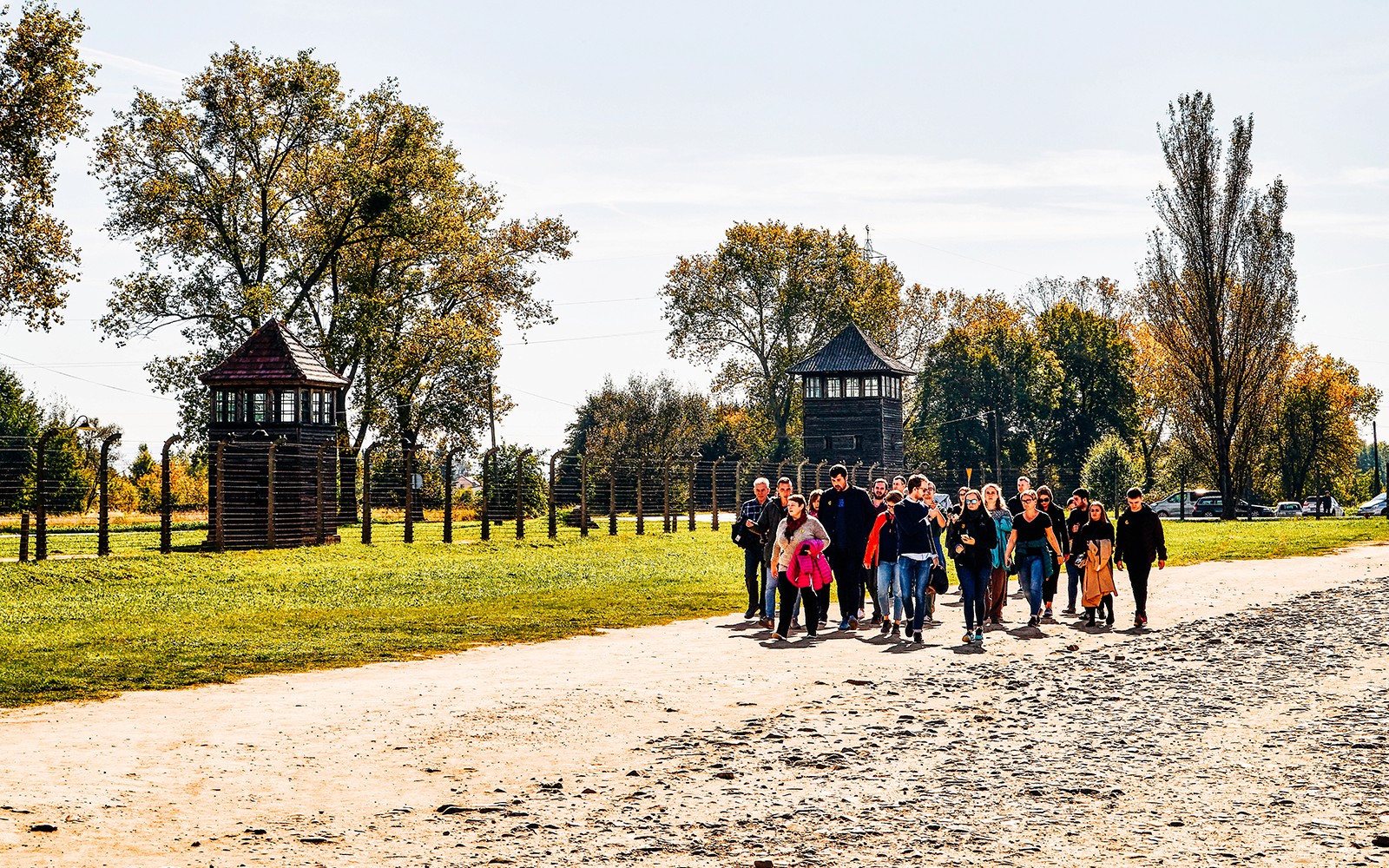 Grupp som promenerar genom Auschwitz-Birkenau med vakttorn i bakgrunden, en del av Krakow-turen.