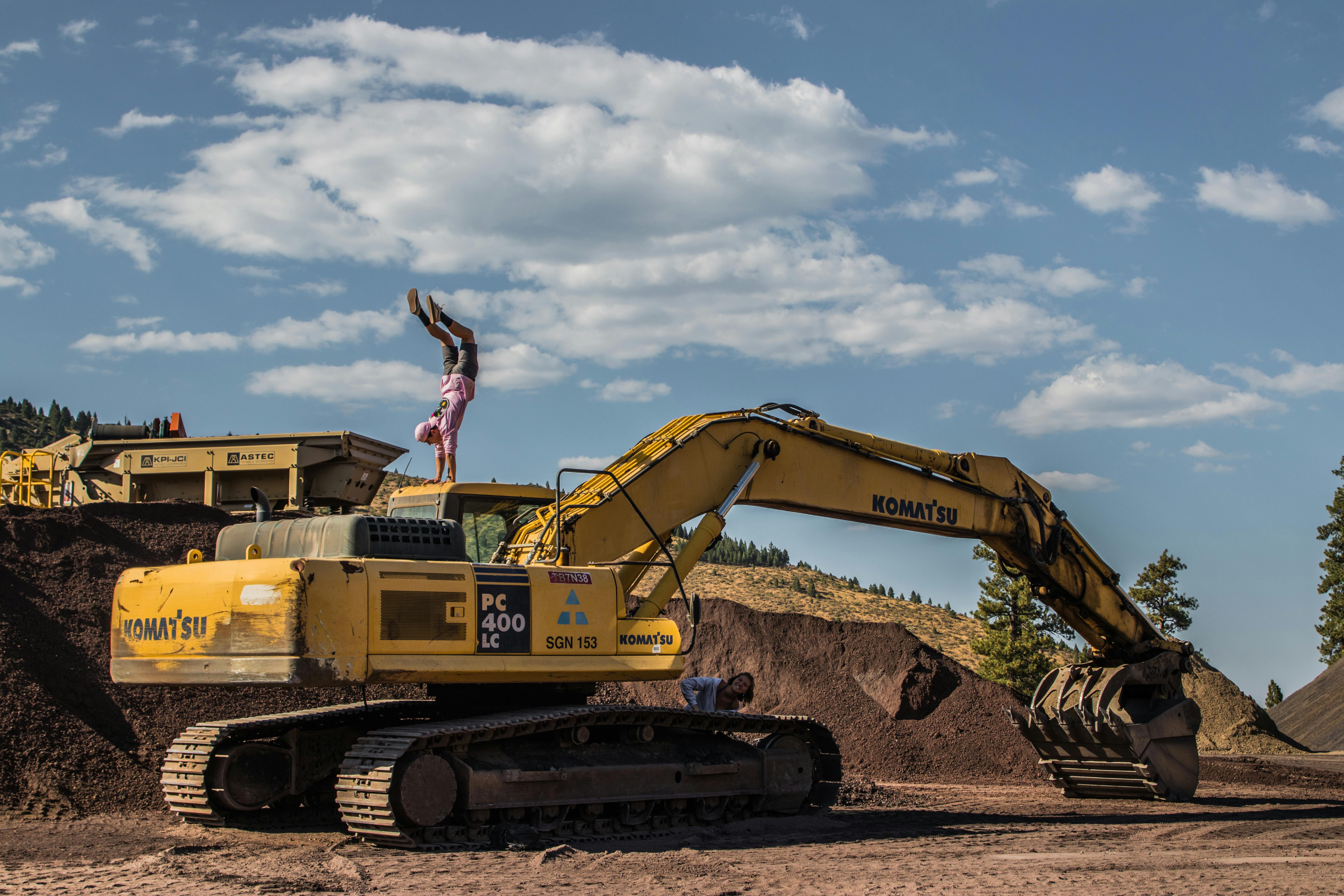 Komatsu excavator moving soil on a grading and earthwork job site under clear skies.