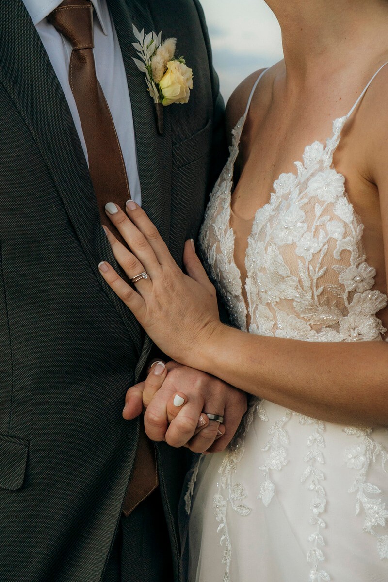 Close-up of wedding rings while couple holds hands
