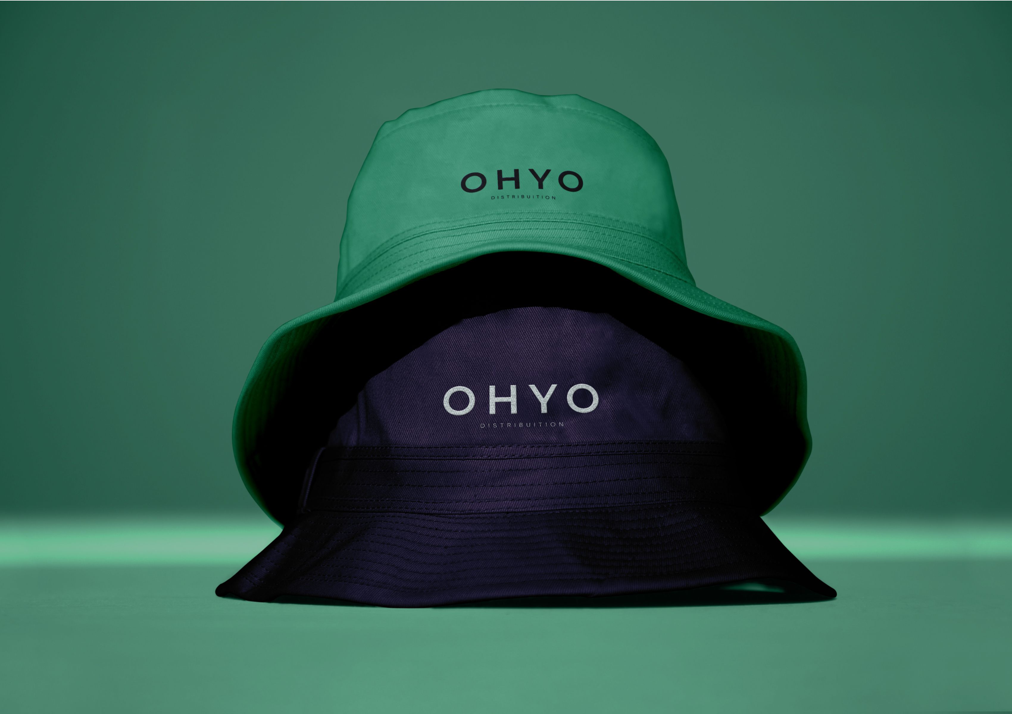 OHYO branded hats in green and navy, representing company’s visual identity and merchandise.
