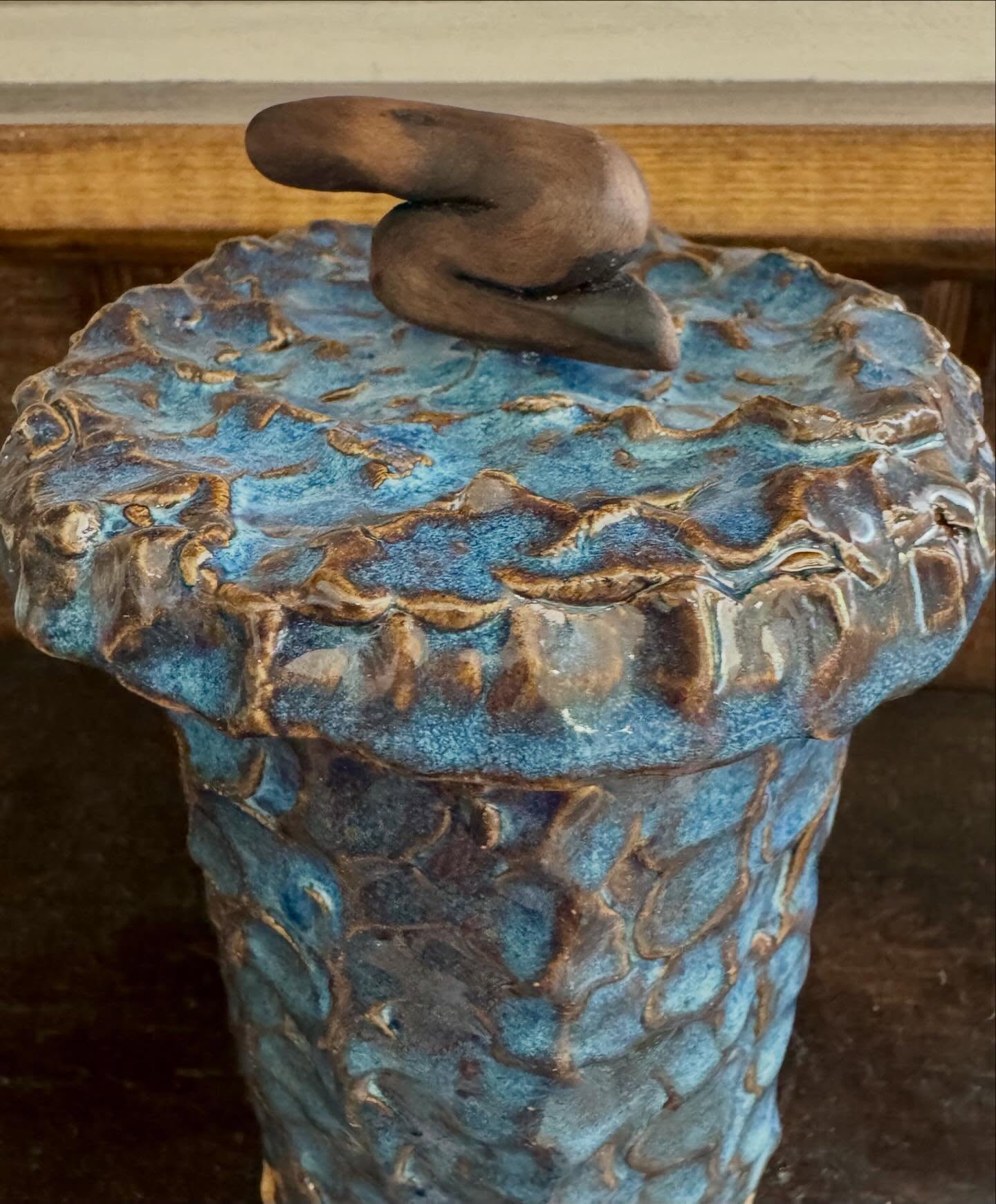 Close view of the jar's textured lid and curving wood handle