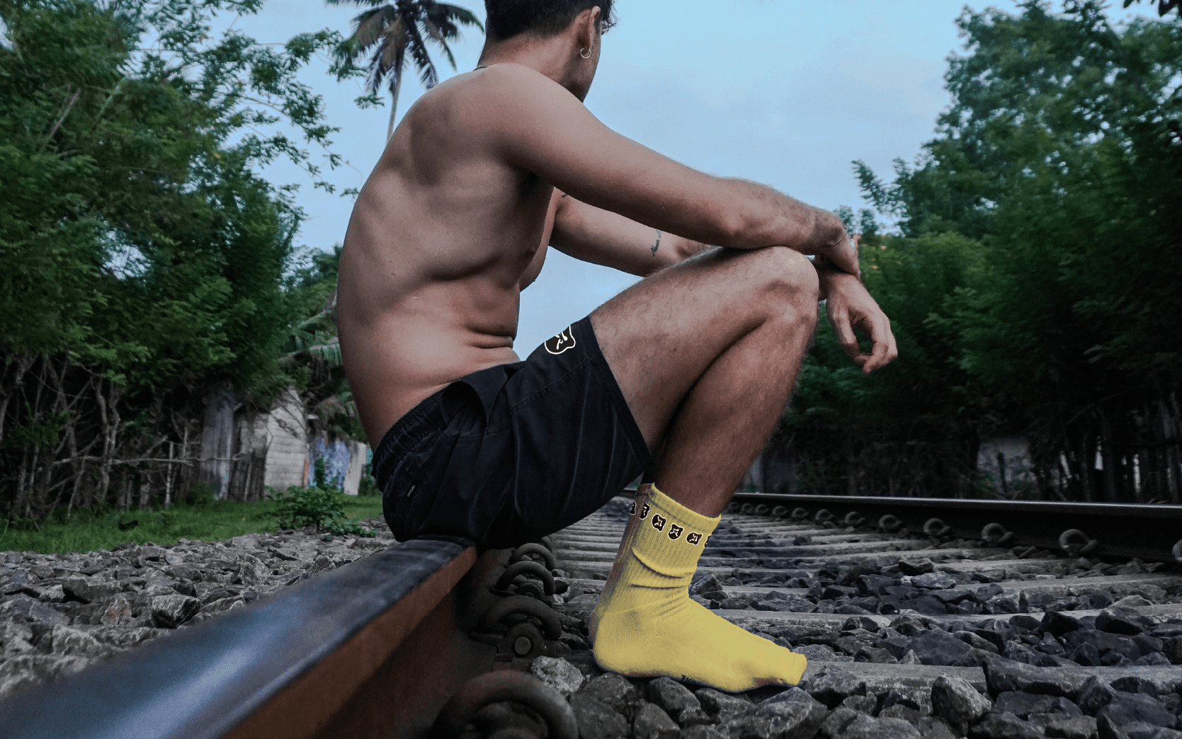 Mad Face Yellow Socks on young man sitting on trail rail