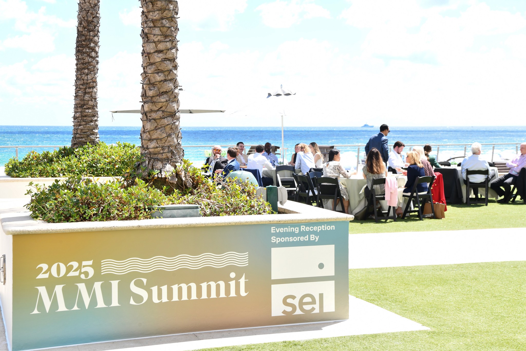 2025 MMI Summit outdoor patio on a sunny day overlooking the beach with an MMI branded vinyl cling on a planter in the foreground