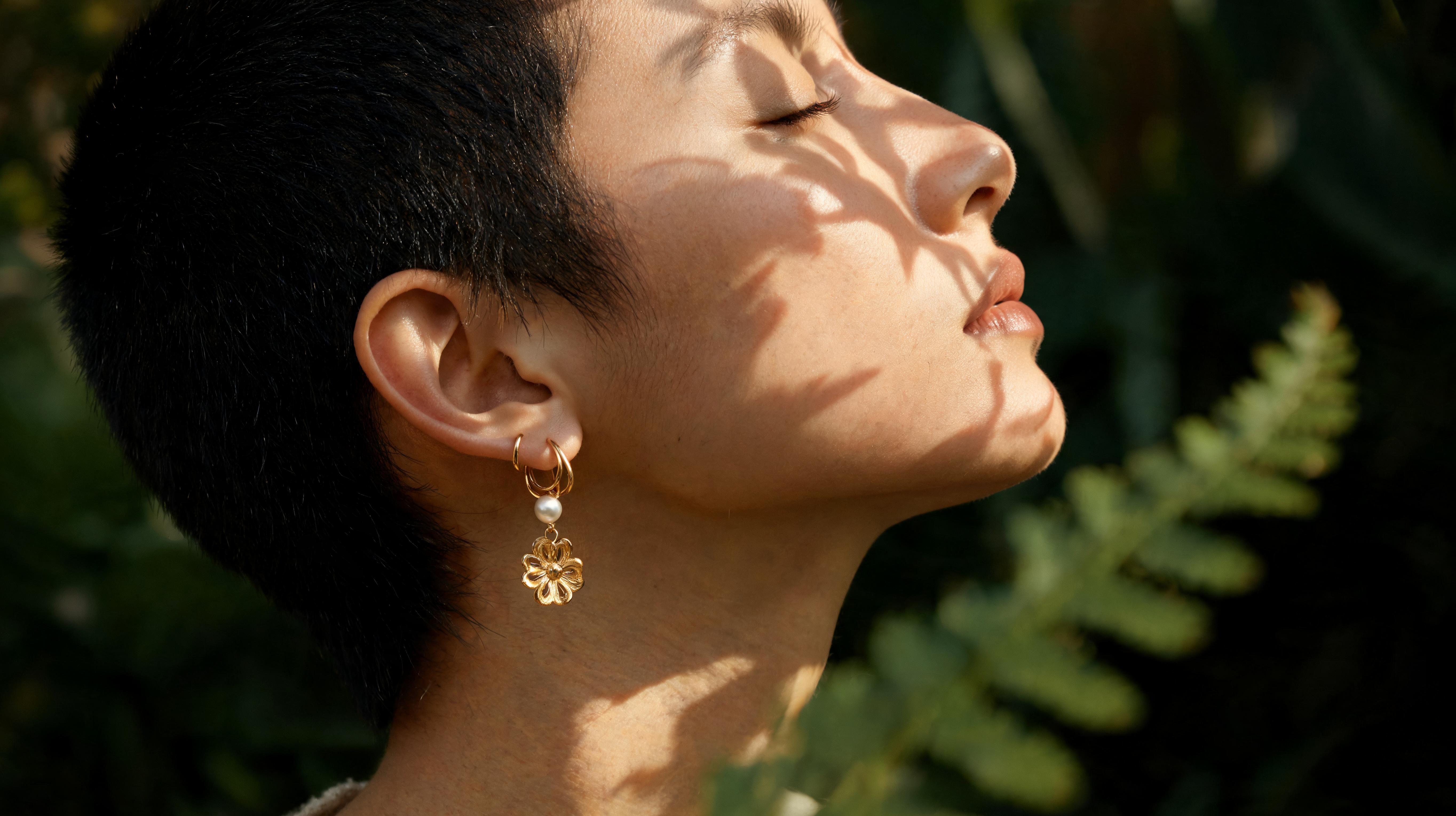 A woman in a black camisole and light jeans resting her chin on her knee, a thin gold ring on one finger