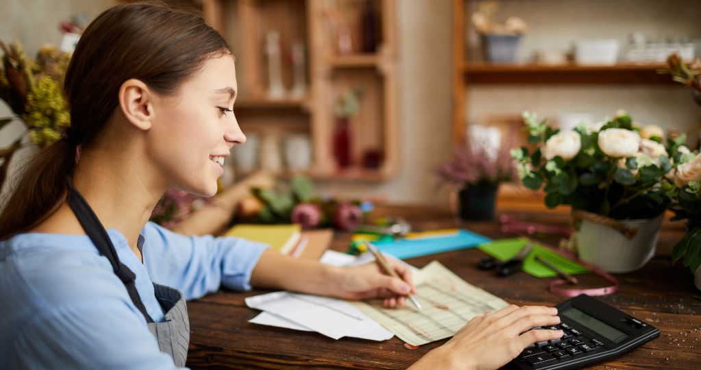 Woman managing TikTok shop finances with calculator and flowers